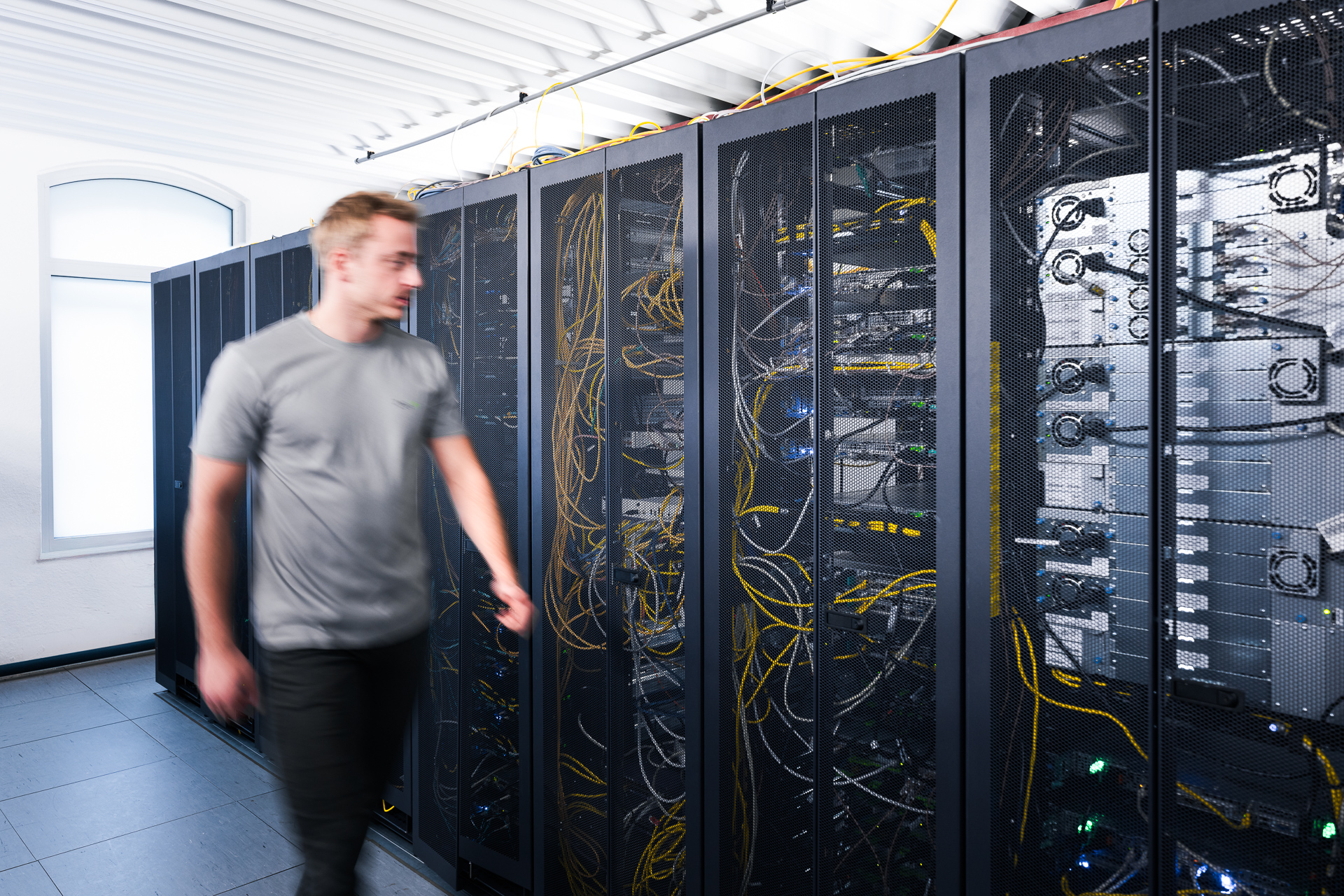 Mitarbeiter läuft an einem Serverschrank entlang.